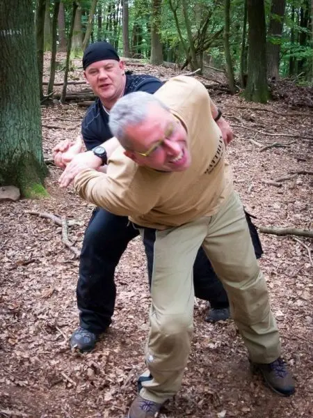 Zwei Personen üben eine Selbstverteidigungstechnik im Wald aus