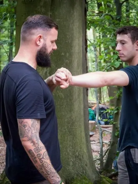 Zwei Personen üben eine Technik zur Handbefreiung an einem Baum im Wald
