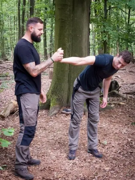 Zwei Personen üben eine Technik zur Handbefreiung im Wald