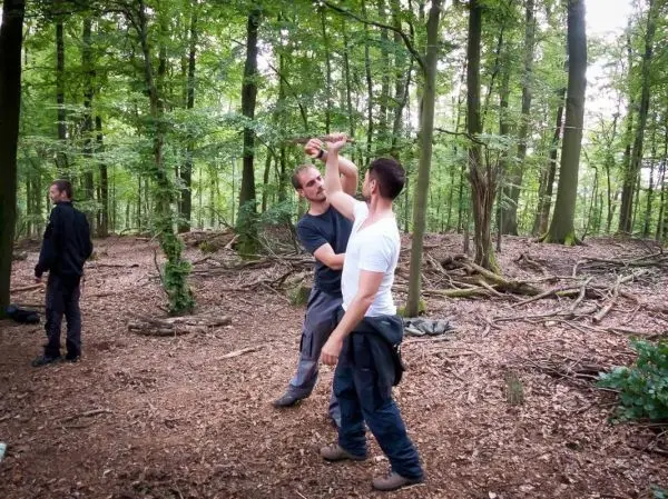 Zwei Personen üben eine Technik zur Selbstverteidigung im Wald