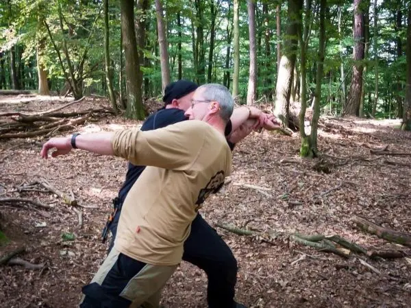 Zwei Personen üben eine Technik zur Selbstverteidigung im Wald