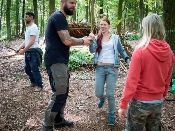 Zwei Personen übergeben sich einen Stapel Äste im Wald