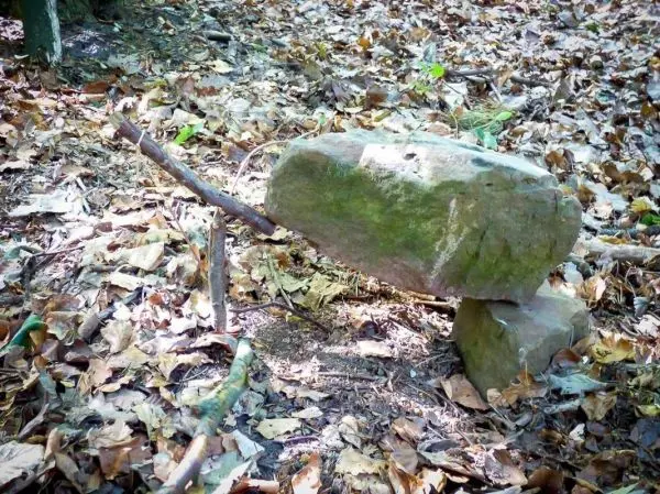 Ein großer Stein liegt auf zwei kleineren Steinen im Laub