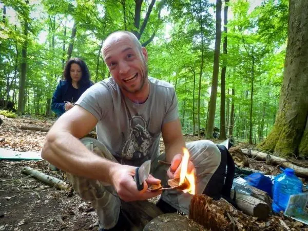 Feuerstahl entzündet Zunder auf einem Holzstück im Wald