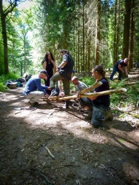Gruppe arbeitet gemeinsam an einem Holzprojekt im Wald beim Survival Training