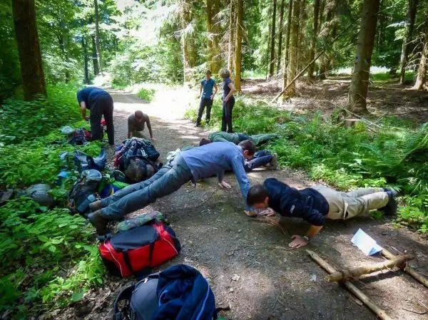 Gruppentraining im Wald, Teilnehmer führen Liegestütze auf einem Waldweg aus