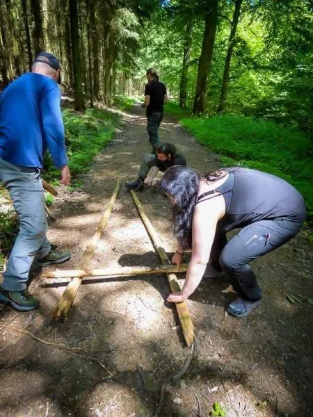 Gruppierung baut selbstgebaute Seilbrücke aus Holzstücken auf einem Waldweg