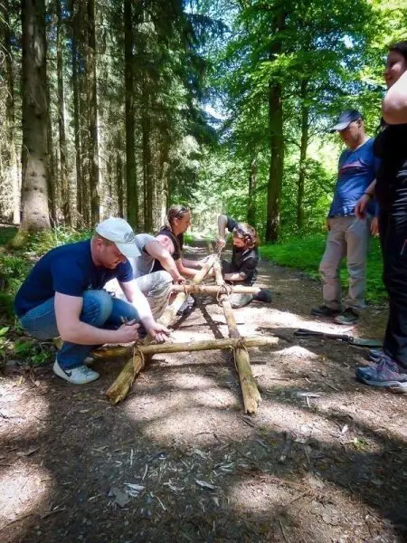 Gruppierung baut selbstgebaute Trage aus Holzstöcken im Wald