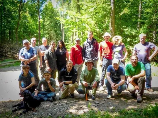 Gruppierung von Personen im Wald, umgeben von Bäumen und natürlicher Vegetation