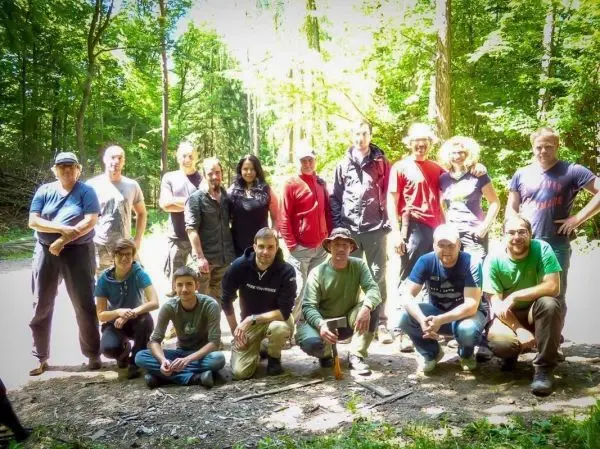 Gruppierung von Personen im Wald, umgeben von Bäumen und natürlicher Vegetation