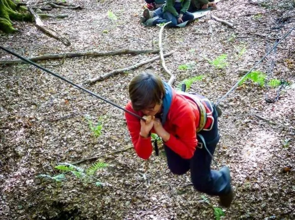 Junge überquert selbstgebaute Seilbrücke im Wald