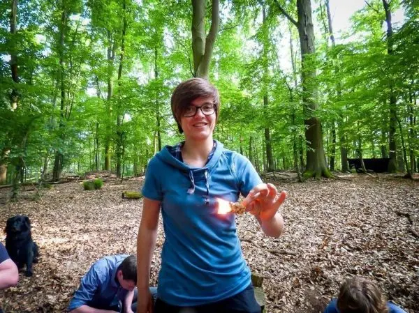 Kleine Flamme in Hand, umgeben von Wald und Laub