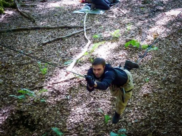 Mann überquert eine selbstgebaute Seilbrücke im Wald