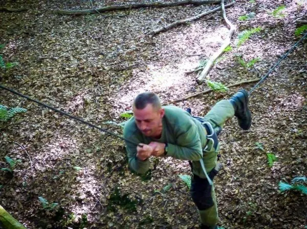 Mann überquert eine selbstgebaute Seilbrücke im Wald