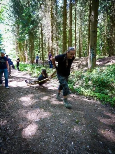 Mann zieht improvisierte Trage mit Person durch den Wald