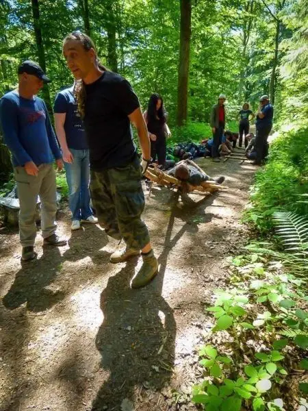 Mann zieht improvisierte Trage mit Person durch den Waldweg
