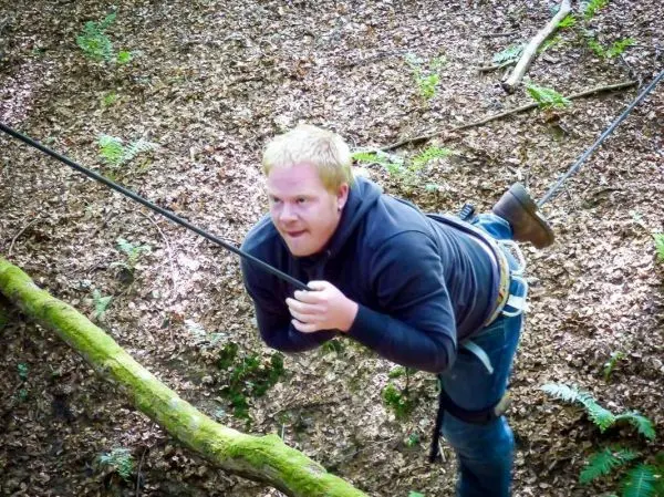 Person schwingt an einem Seil zwischen Bäumen