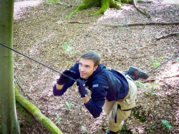 Person schwingt an einem Seil zwischen Bäumen