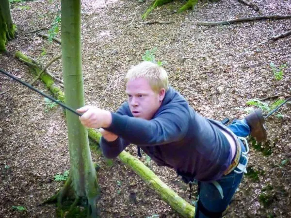 Person schwingt an einem Seil zwischen Bäumen beim Überlebenstraining