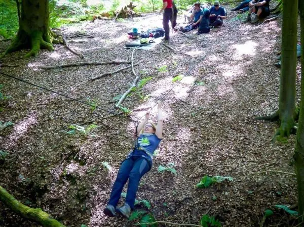 Person schwingt an Seil über den Boden im Wald beim Überlebenstraining