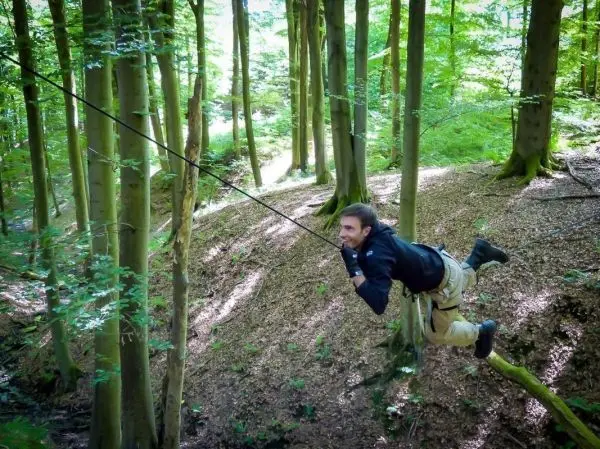 Person schwingt an Seil zwischen Bäumen