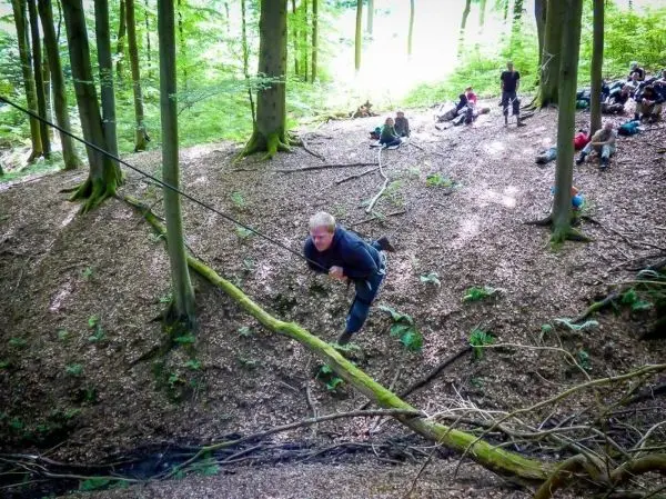 Person überquert selbstgebaute Seilbrücke im Wald beim Survival Training