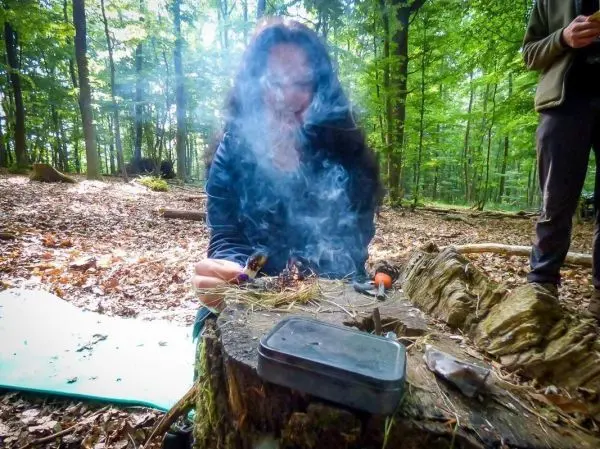 Person zündet Feuer auf einem Baumstumpf im Wald