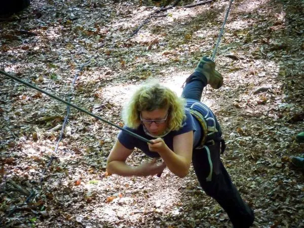 Seilquerung mit gesichertem Klettergurt und Seil im Wald