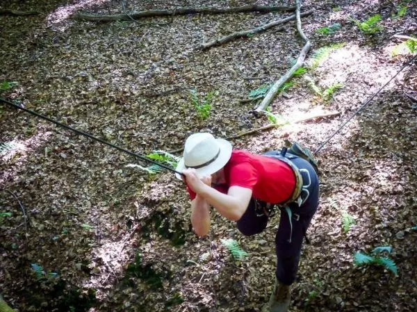 Seilquerung mit gesichertem Klettergurt und Seil im Wald