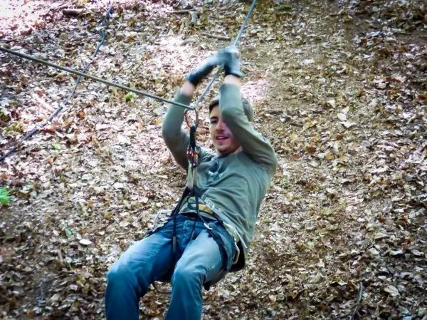 Seilquerung mit Sicherheitsgeschirr und Karabiner in einem Waldgebiet