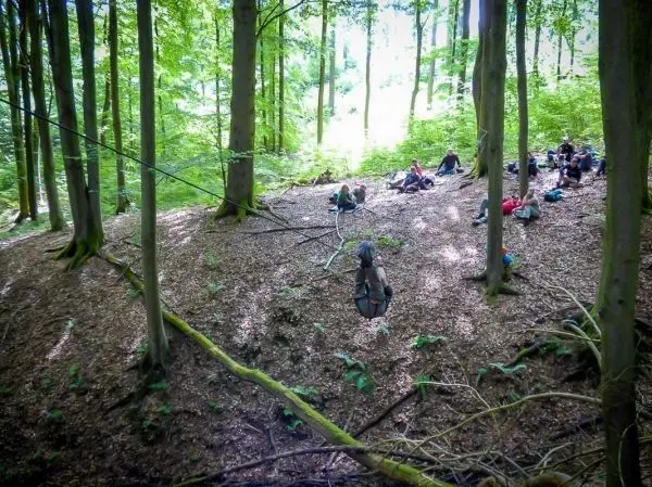 Selbstgebaute Seilquerung über einen Hang, Teilnehmer sitzen im Laub