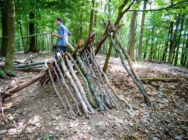 Selbstgebaute Tarp-Notunterkunft aus Ästen im Wald
