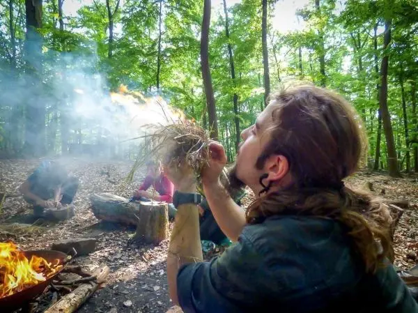 Zunder glimmt in den Händen, während Rauch aufsteigt