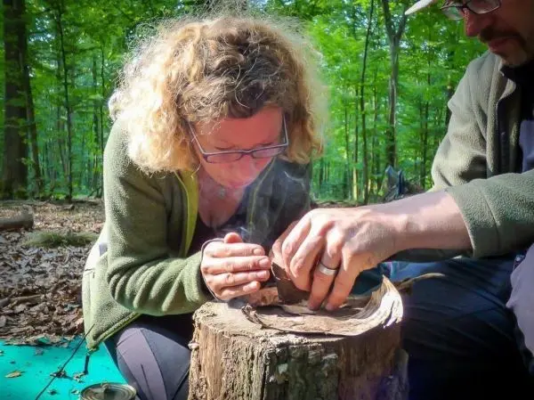 Zunder wird durch Reibung zwischen Holzstücken entzündet