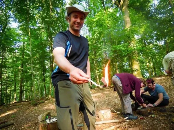 Feuerstahl entzündet Zunder in der Hand, während andere am Boden arbeiten