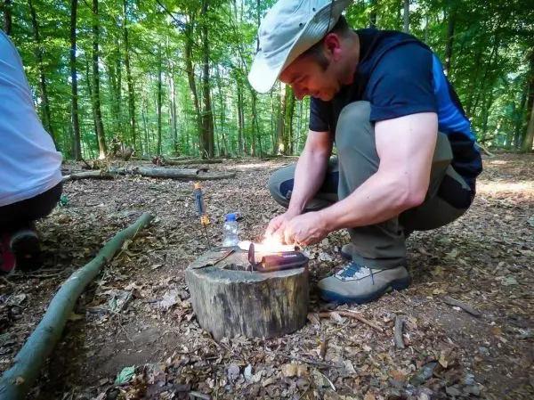 Feuerstahl erzeugt Funken auf Zunder auf einem Baumstumpf im Wald
