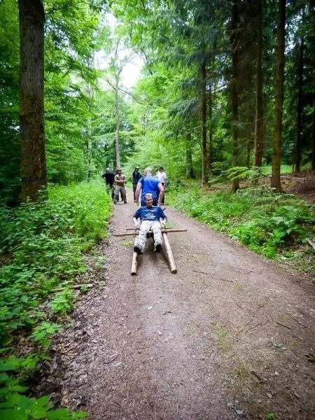 Gruppierung zieht improvisierte Trage mit Person durch den Waldweg
