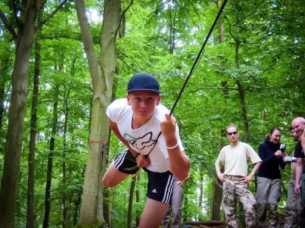 Junge überquert selbstgebaute Seilbrücke zwischen Bäumen im Wald