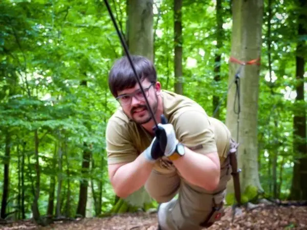 Mann überquert eine selbstgebaute Seilbrücke im Wald