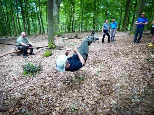 Mann überquert selbstgebaute Seilbrücke zwischen Bäumen im Wald