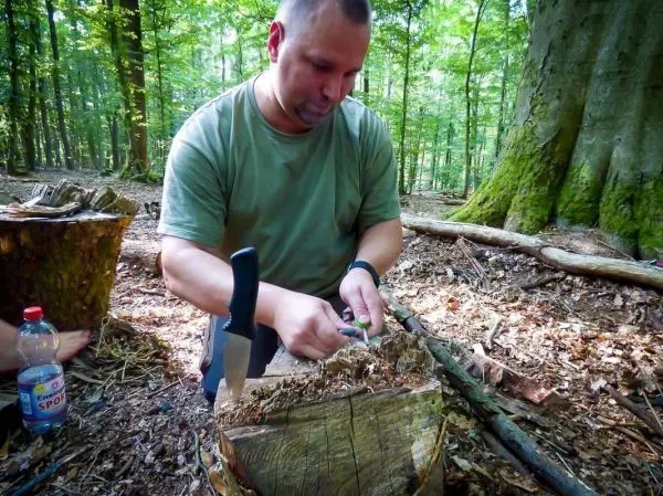 Messer schneidet Holzstück auf einem Baumstumpf im Wald