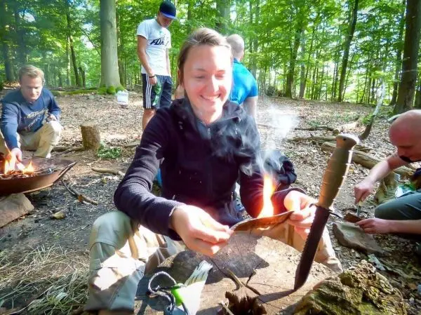 Person hält brennendes Material in der Hand beim Feuer machen