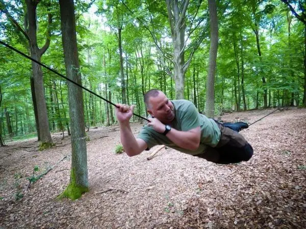 Person schwingt an einer Seilüberquerung durch den Wald beim Survival Training