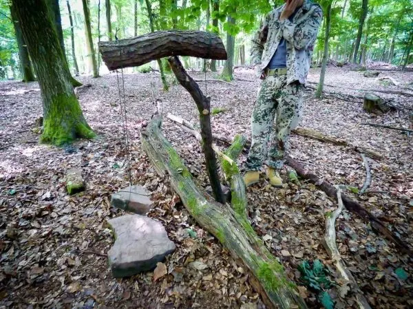 Person steht neben einer selbstgebauten Wippe im Wald