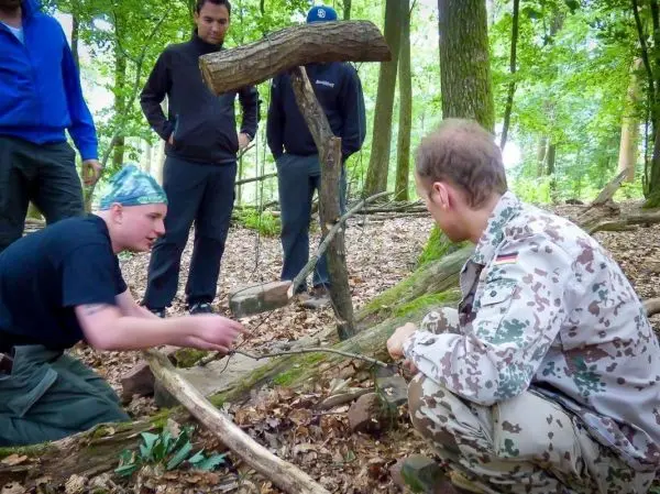 Person zeigt einer anderen Person eine Falle im Wald
