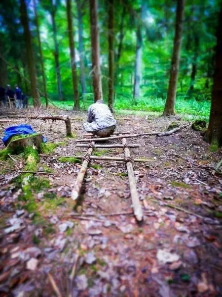 Selbstgebaute Konstruktion aus Ästen liegt auf dem Boden im Wald