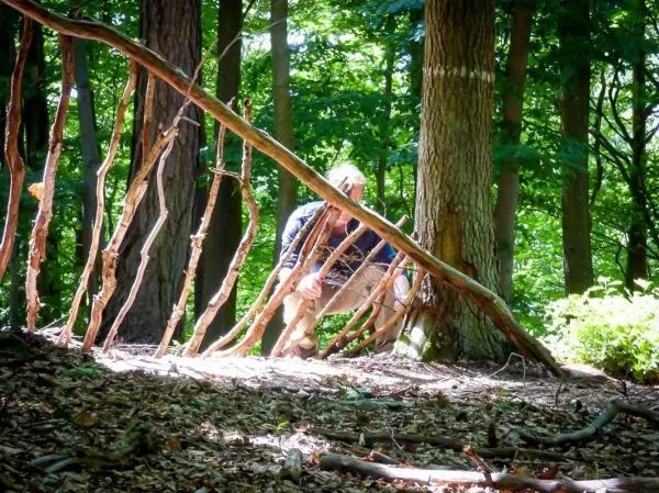 Selbstgebaute Konstruktion aus Ästen steht zwischen Bäumen im Wald