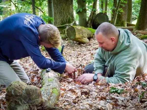 Zwei Personen bauen eine Falle im Wald auf