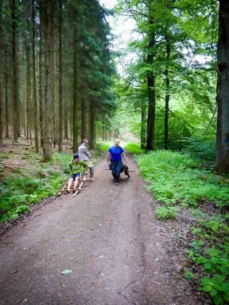 Zwei Personen ziehen eine improvisierte Trage auf einem Waldweg