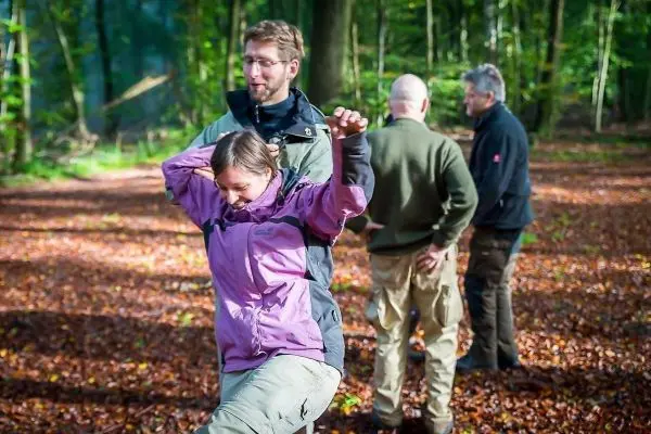 Eine Person balanciert auf einem Bein, während andere im Hintergrund stehen